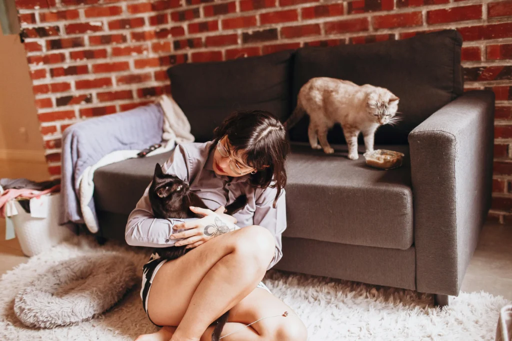 Tutora interagindo com dois gatos em ambiente aconchegante, representando bem-estar e hidratação felina com fonte inox 3L.